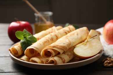 Delicious rolled thin pancakes on wooden table