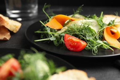 Delicious vegetable salad with microgreen on black table, closeup