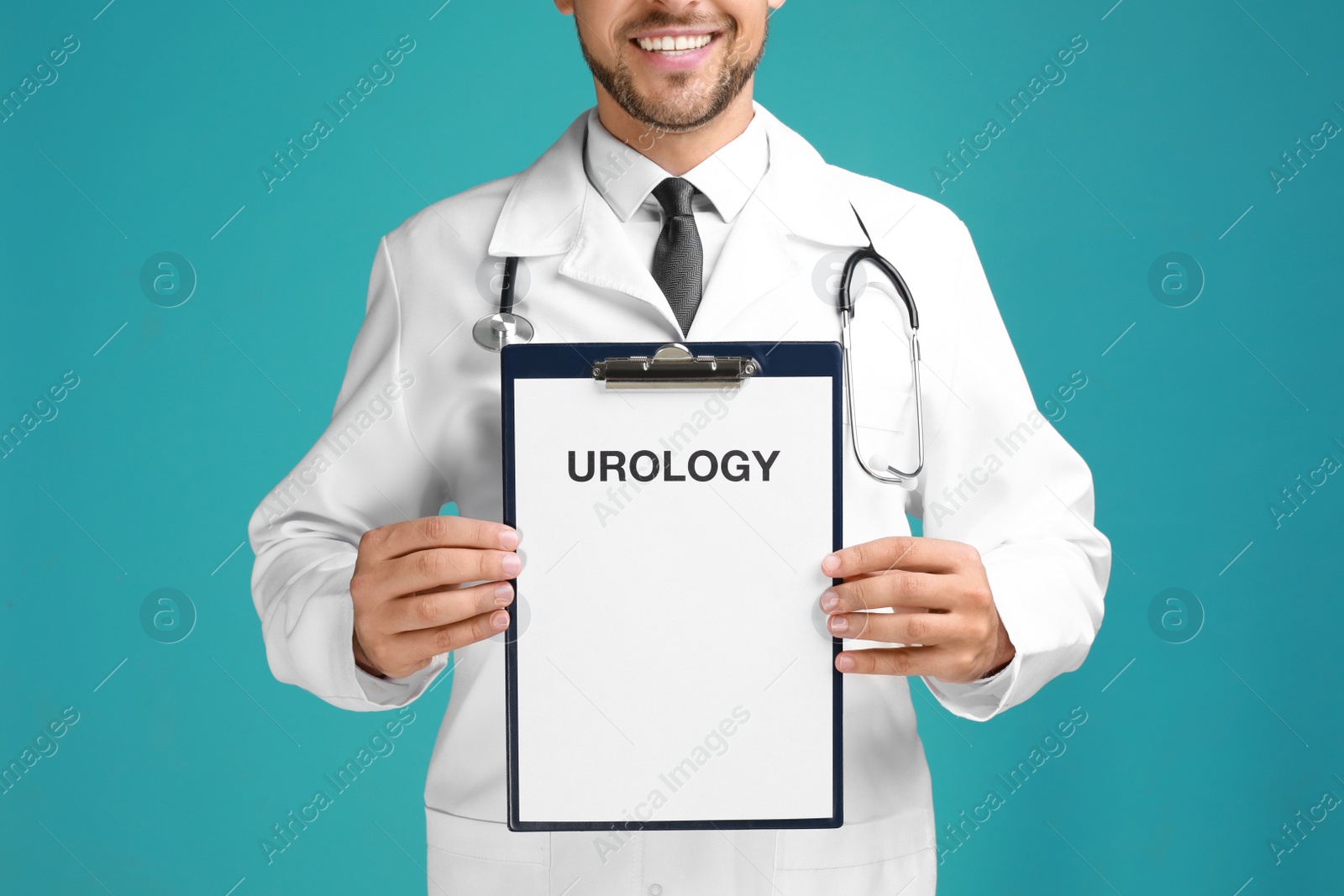 Photo of Male doctor holding clipboard with word UROLOGY on turquoise background, closeup