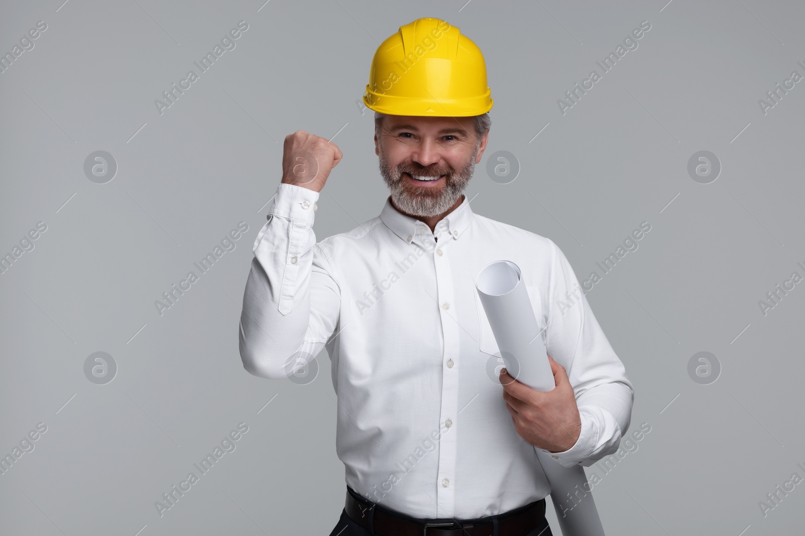 Photo of Architect in hard hat holding draft on grey background