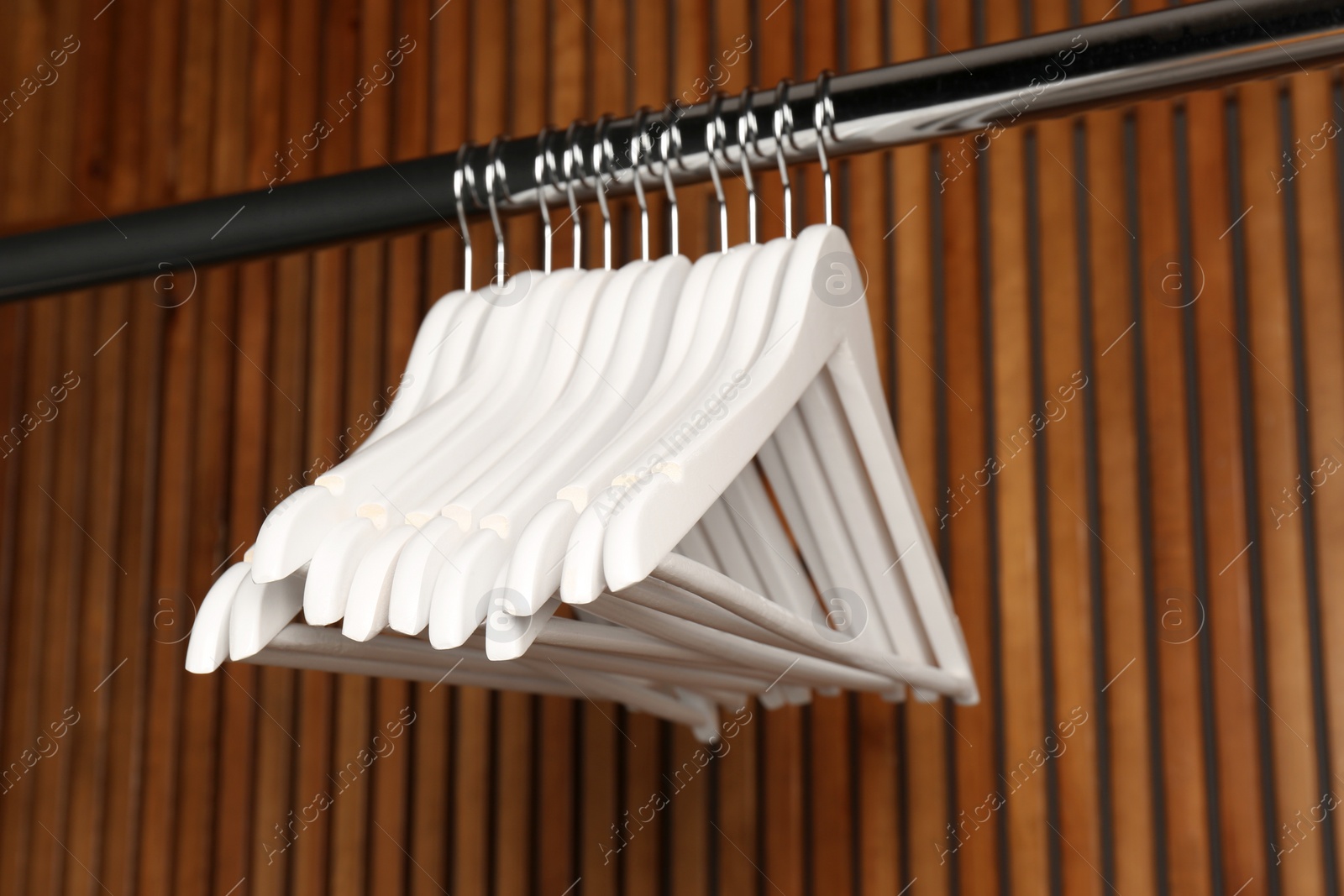 Photo of Empty hangers on rail against wooden background