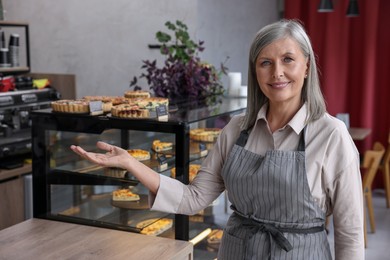 Photo of Happy business owner inviting to come into her cafe