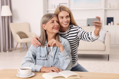 Photo of Happy mature mother and her daughter taking selfie at home