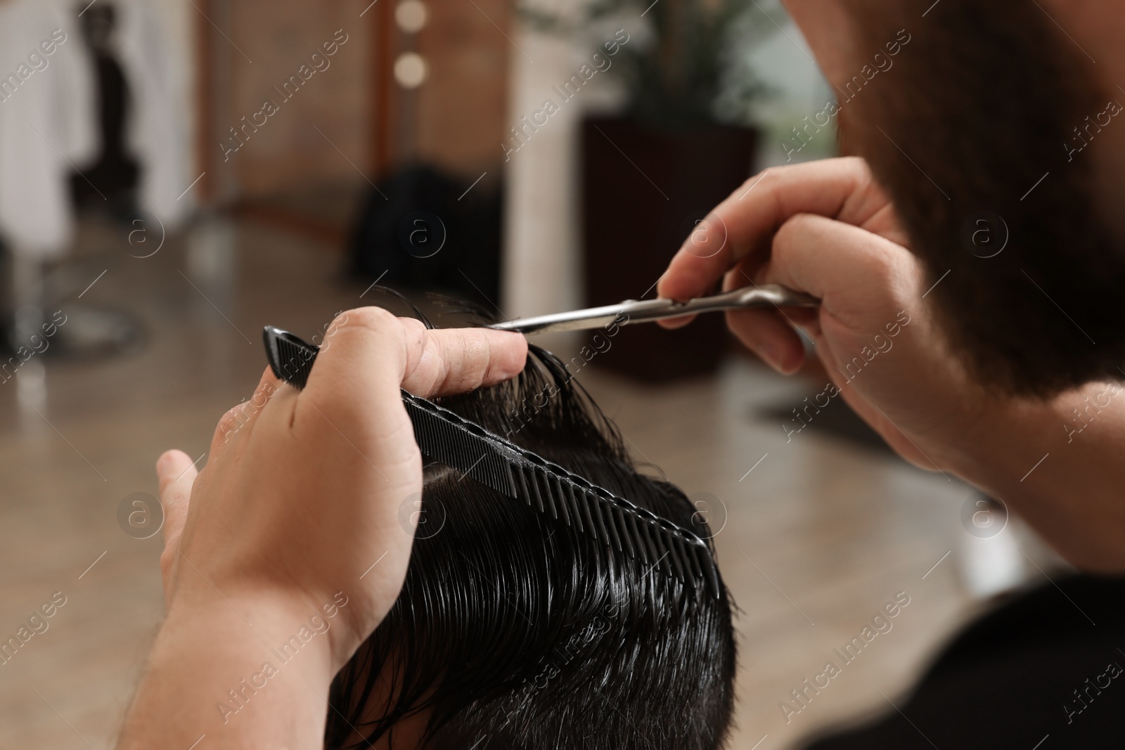 Photo of Professional hairdresser working with client in barbershop, closeup