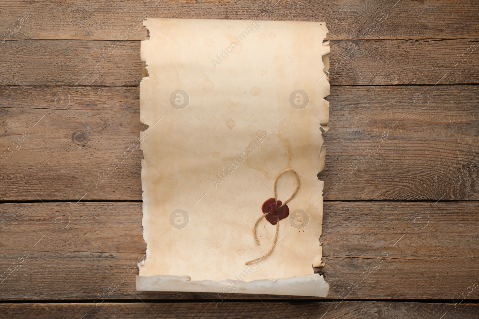 Photo of Sheet of old parchment paper with wax stamp on wooden table, top view. Space for design