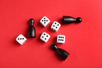 Many white dices and black game pieces on red background, flat lay