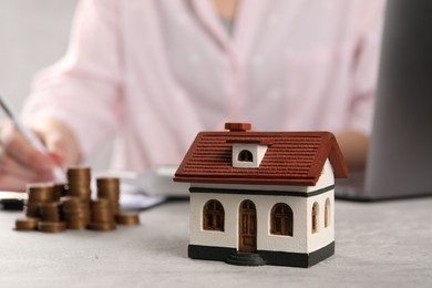 Photo of Woman planning budget at grey table, focus on house model