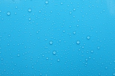 Water drops on light blue background, top view