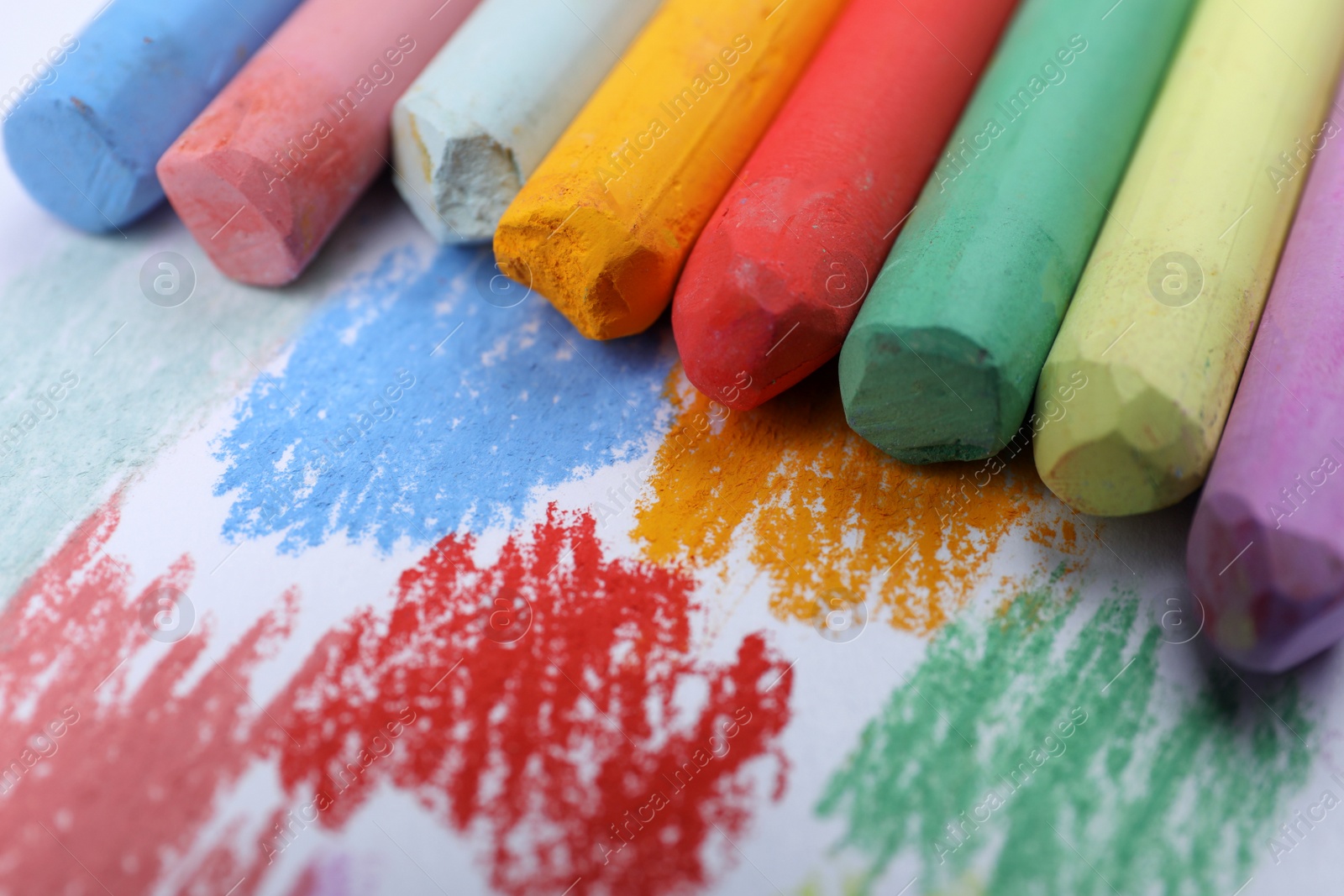 Photo of Colorful pastel chalks and scribbles on white background, closeup. Drawing materials