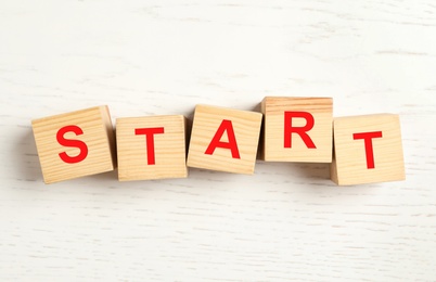 Photo of Word START made with wooden cubes on white background, flat lay