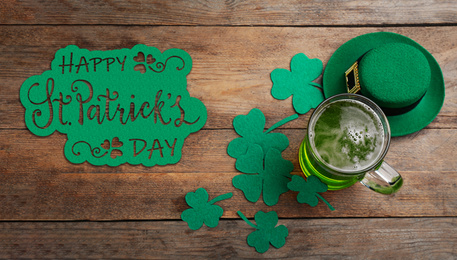 Image of Green beer, hat and clover leaves on wooden table, flat lay. St. Patrick's Day celebration