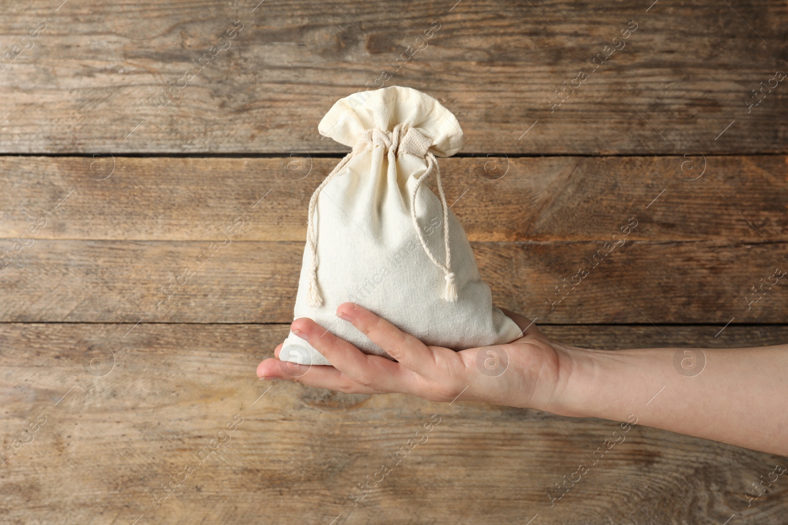 Photo of Woman holding full cotton eco bag on wooden background, closeup