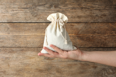 Photo of Woman holding full cotton eco bag on wooden background, closeup