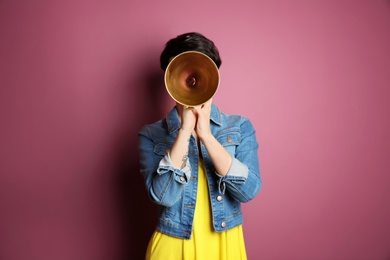 Photo of Young woman with megaphone on color background