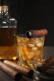 Photo of Cigars and whiskey on grey table against black background