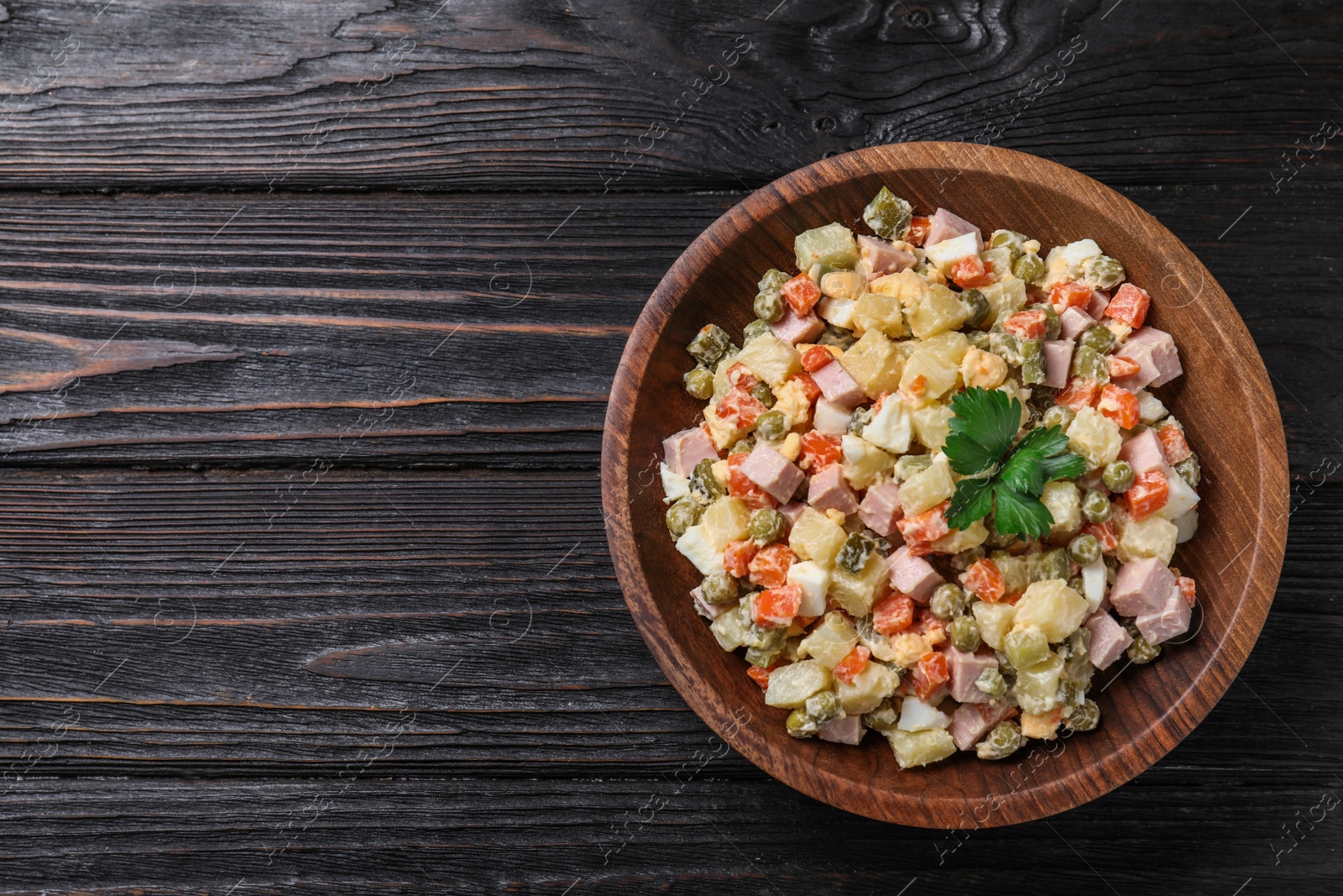 Photo of Delicious salad Olivier on black wooden table, top view. Space for text