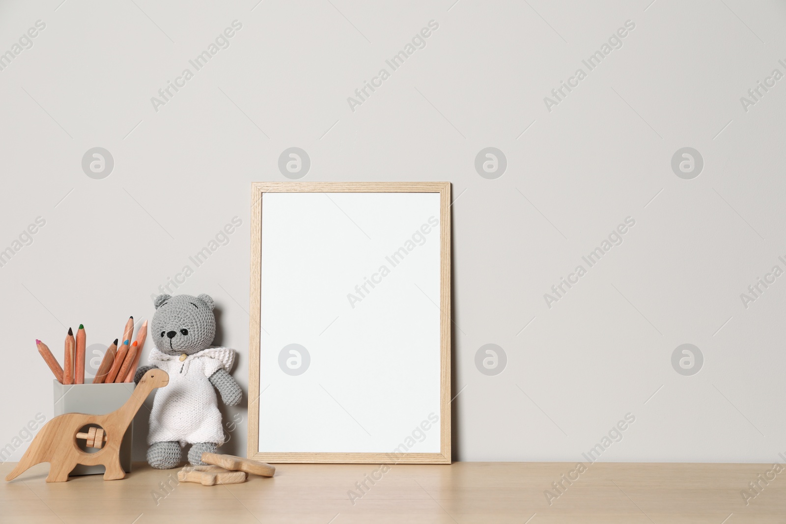 Photo of Empty square frame, stationery and different toys on wooden table, space for text