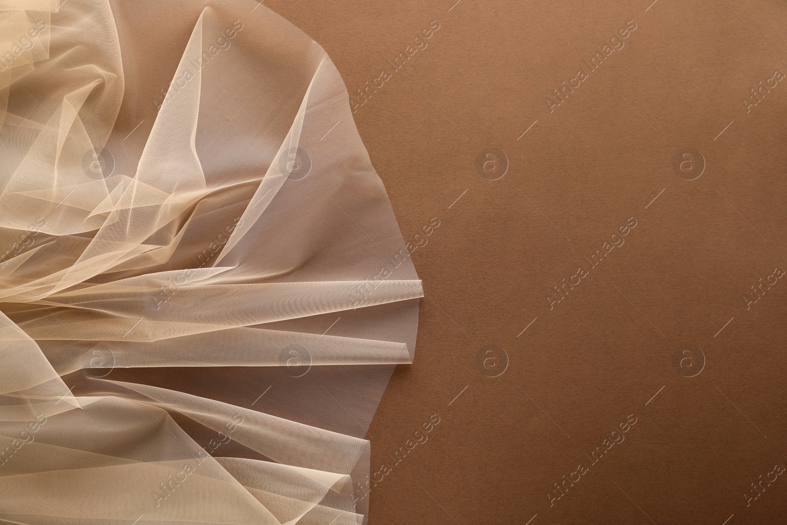 Photo of Beautiful tulle fabric on brown background, top view. Space for text