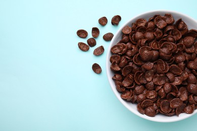 Photo of Breakfast cereal. Chocolate corn flakes in bowl on light blue table, top view. Space for text