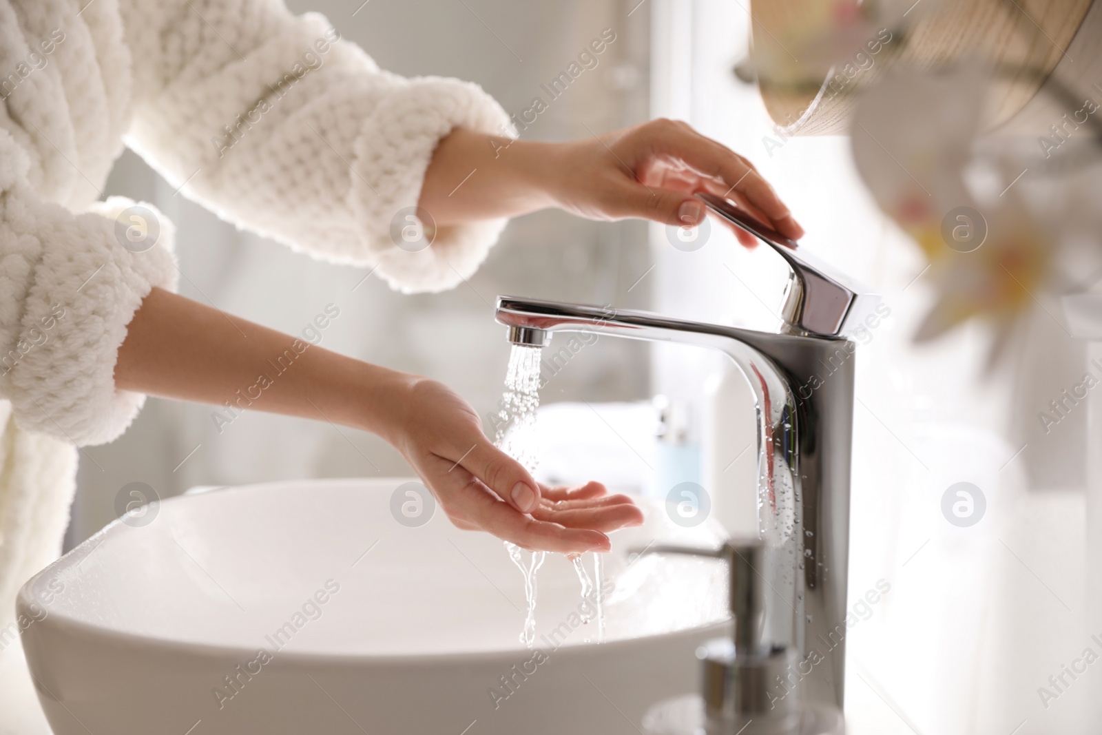 Photo of Woman washing hands over sink in bathroom, closeup