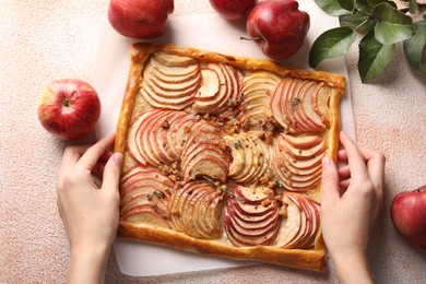 Woman with tasty apple pie at beige textured table, top view