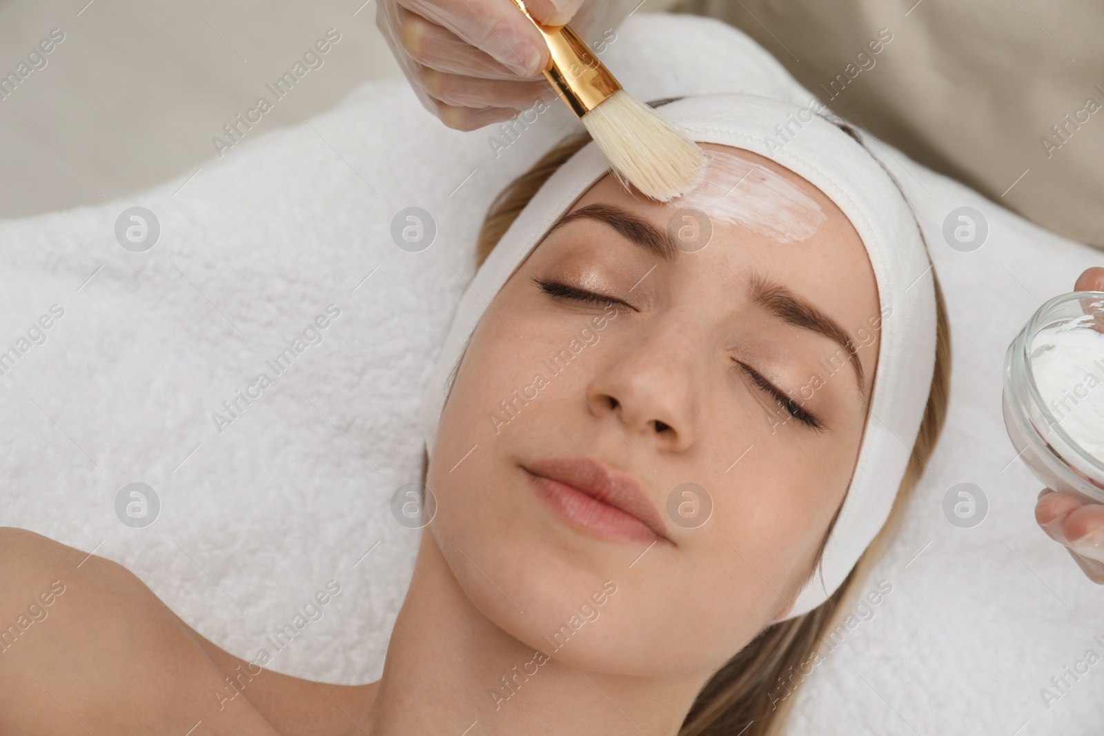 Photo of Young woman during face peeling procedure in salon, above view