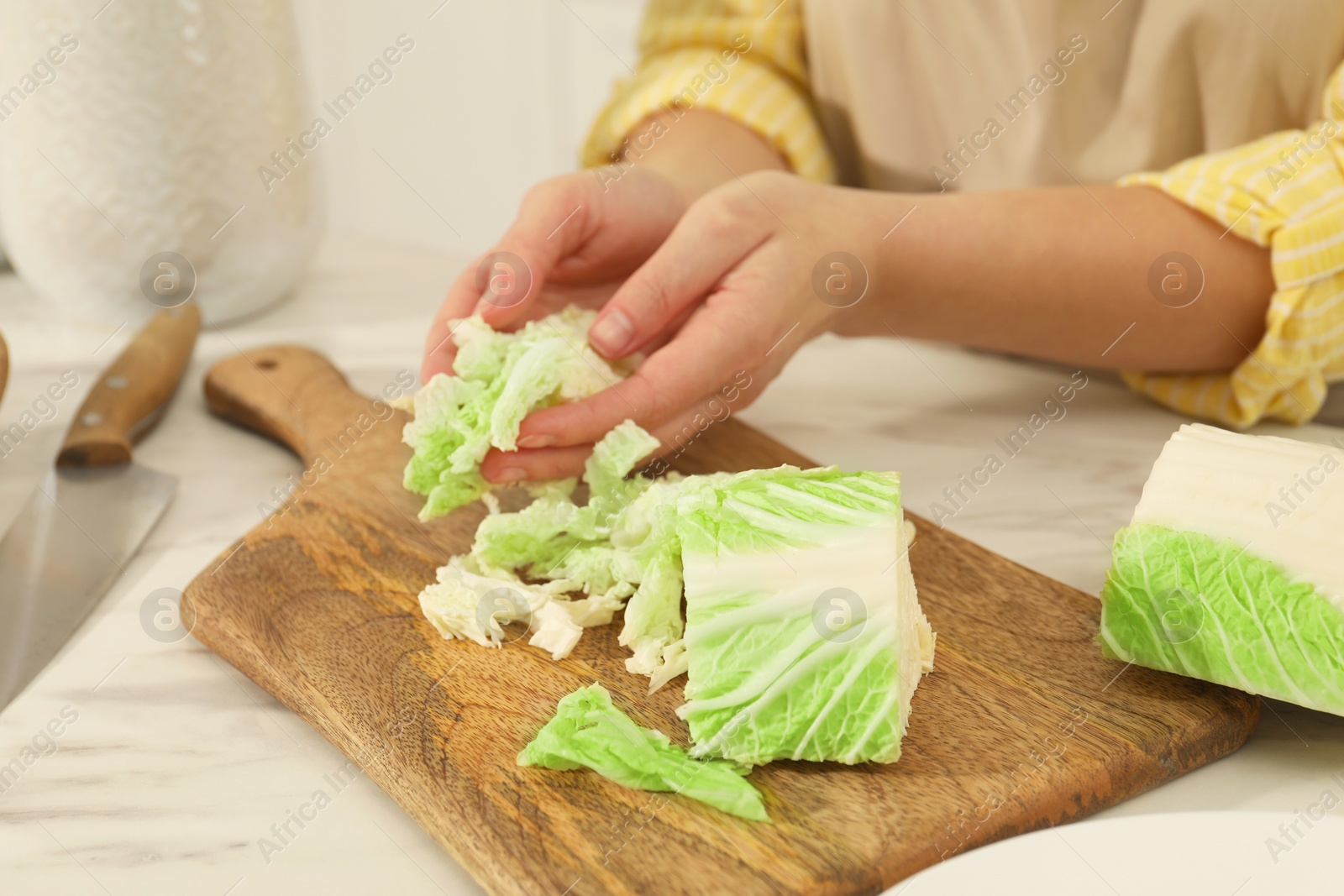 Photo of Woman with cut Chinese cabbage at white kitchen table, closeup