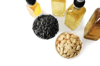 Photo of Bottles of different cooking oils and seeds on white background, above view