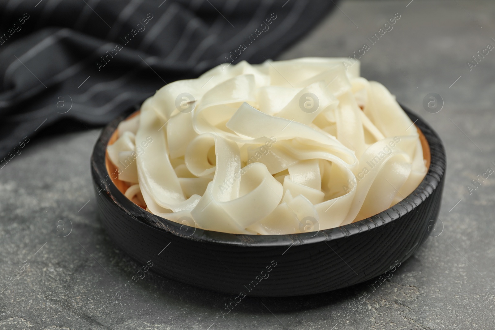 Photo of Tasty cooked rice noodles on grey table, closeup