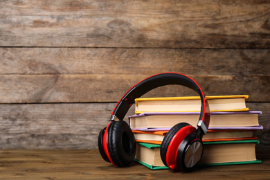 Books and modern headphones on wooden table. Space for text