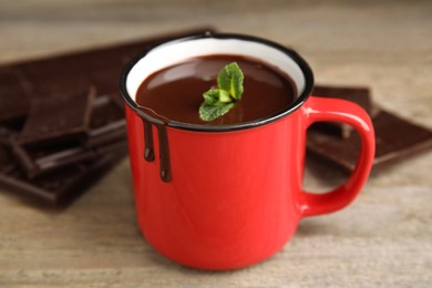 Mug of delicious hot chocolate with fresh mint leaves on wooden table
