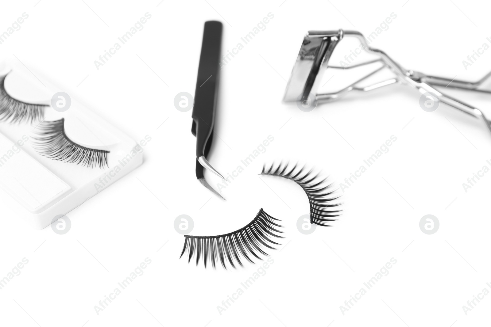 Photo of False eyelashes, tweezers and curler on white background