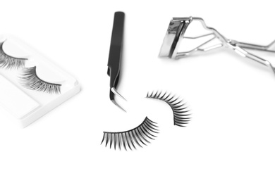 Photo of False eyelashes, tweezers and curler on white background