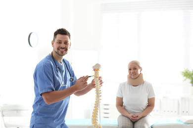 Photo of Male orthopedist explaining structure of spine to patient in clinic