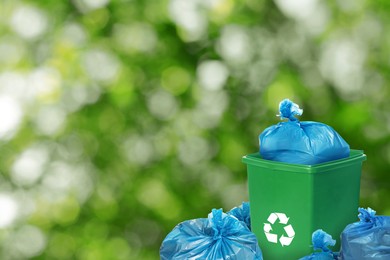 Image of Plastic bags full of garbage and waste bin on blurred background, space for text