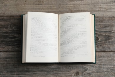 Photo of Open old hardcover book on grey wooden table, top view