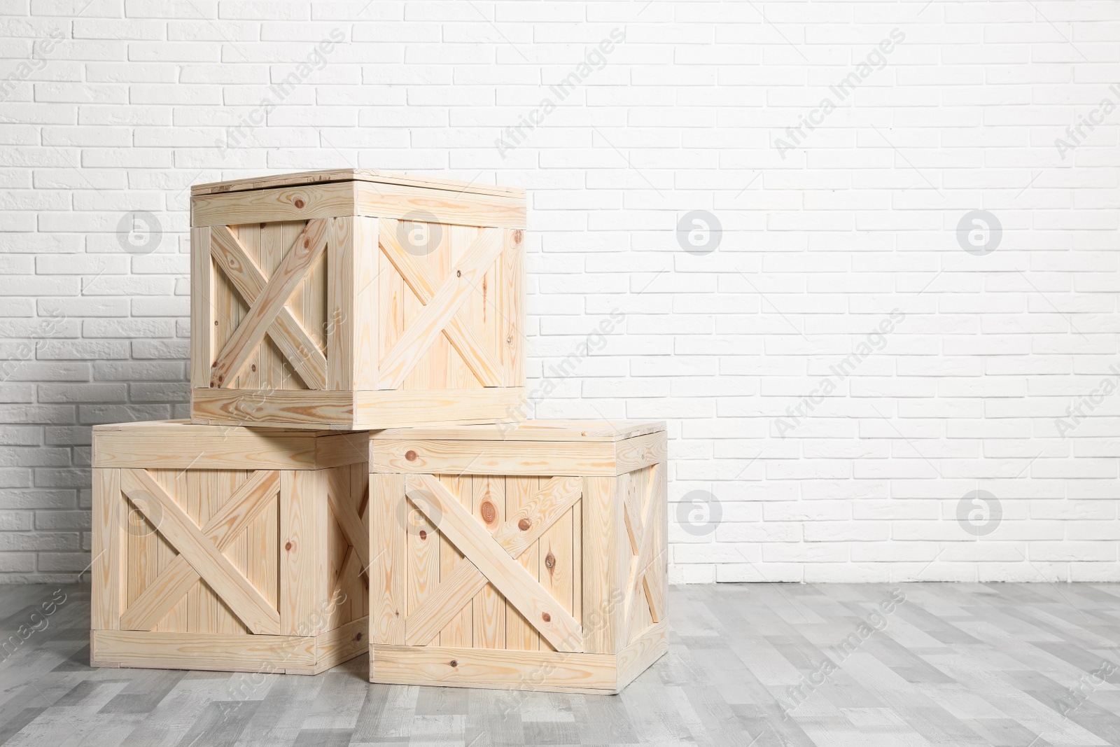 Photo of Wooden crates on floor at white brick wall. Space for text