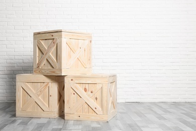 Photo of Wooden crates on floor at white brick wall. Space for text