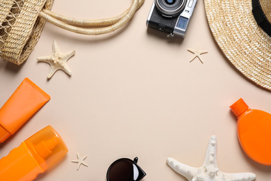 Photo of Flat lay composition with sun protection products and beach accessories on beige background. Space for text