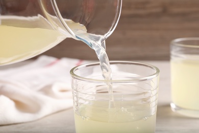 Pouring delicious fresh juice from jug into glass, closeup