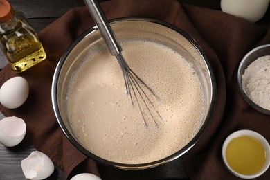 Photo of Dough and whisk in bowl on table, flat lay