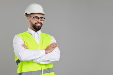 Engineer in hard hat on grey background, space for text