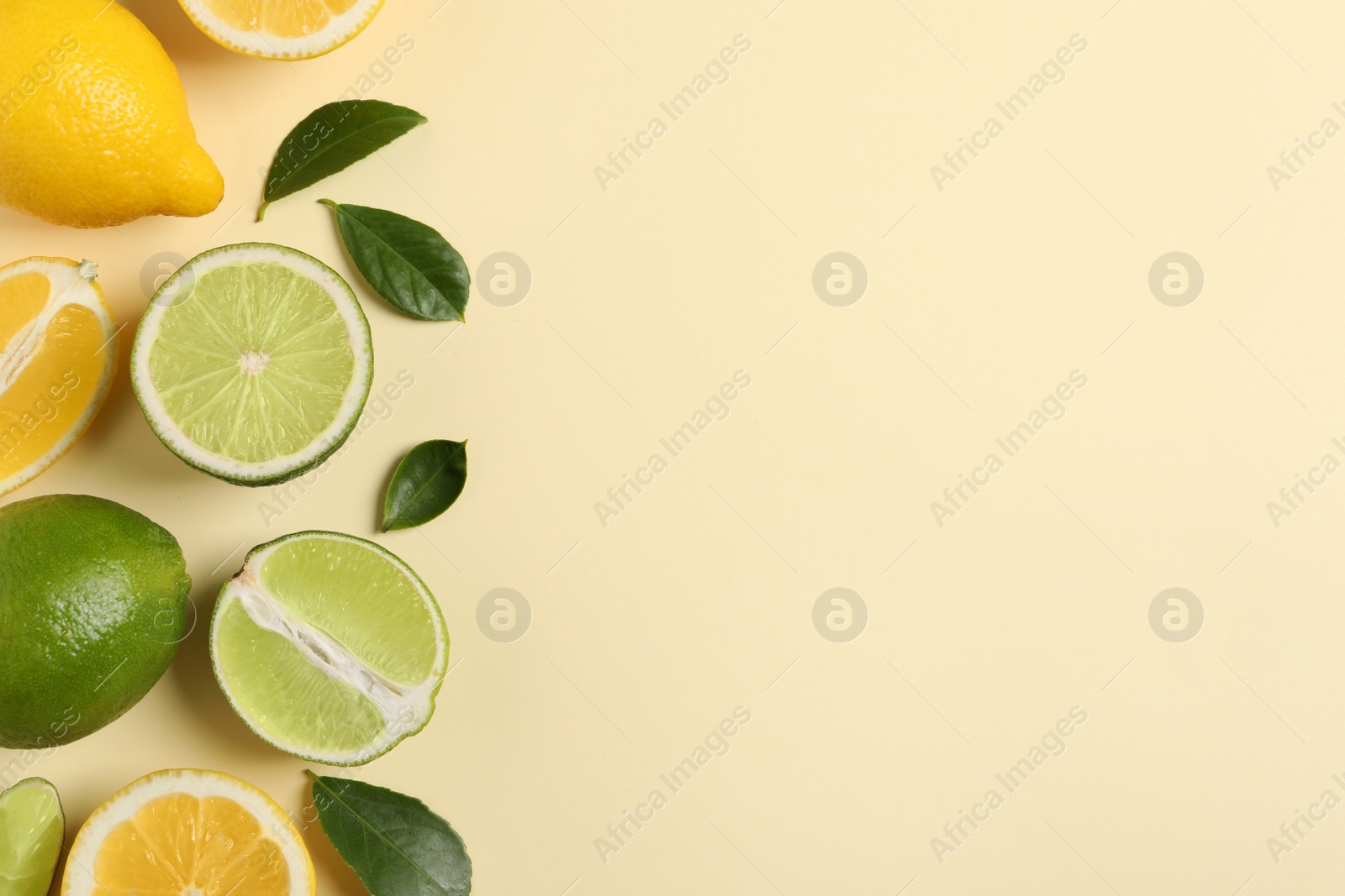 Photo of Fresh ripe lemons, limes and green leaves on beige background, flat lay. Space for text