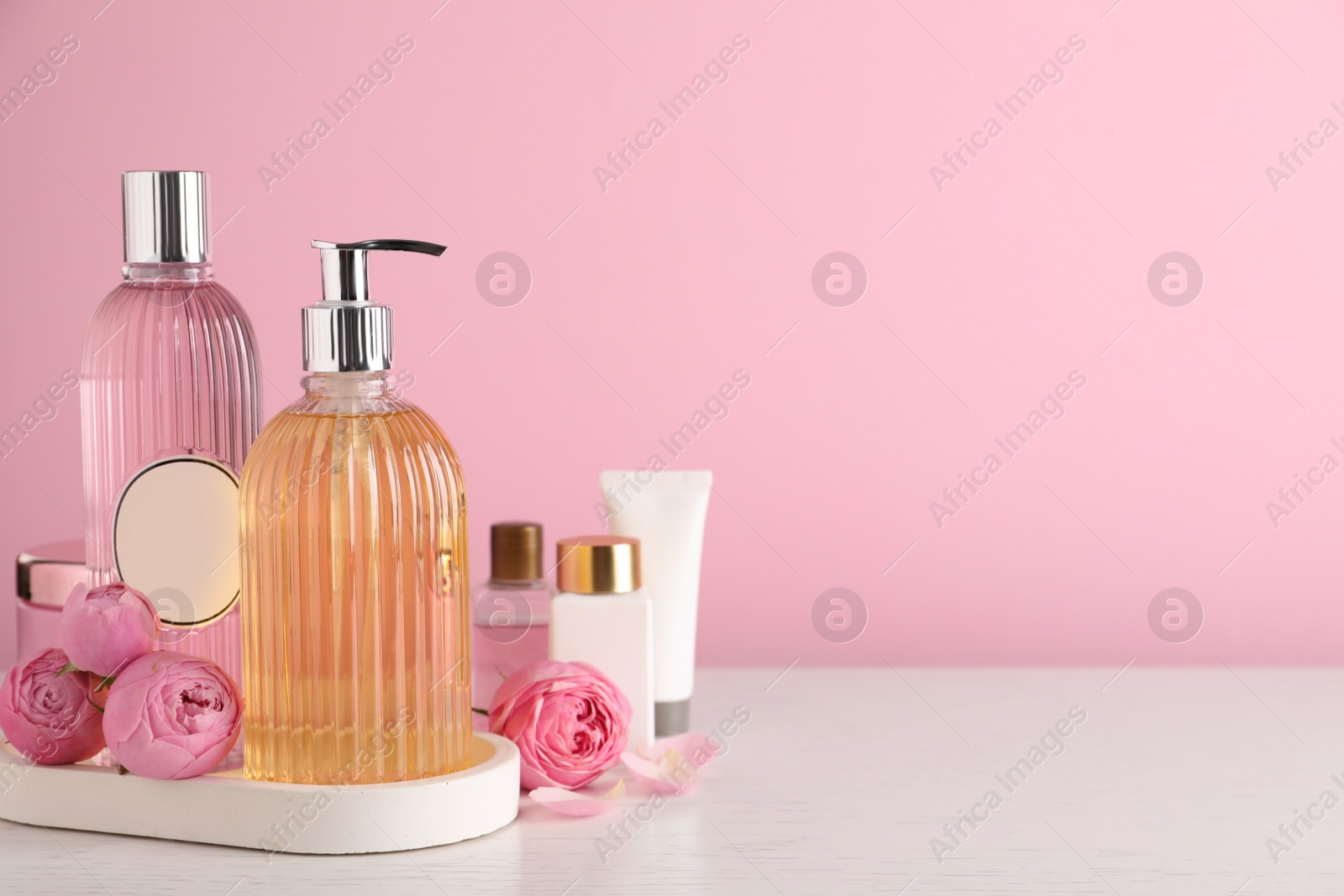 Photo of Cosmetic products and flowers on white wooden table. Space for text