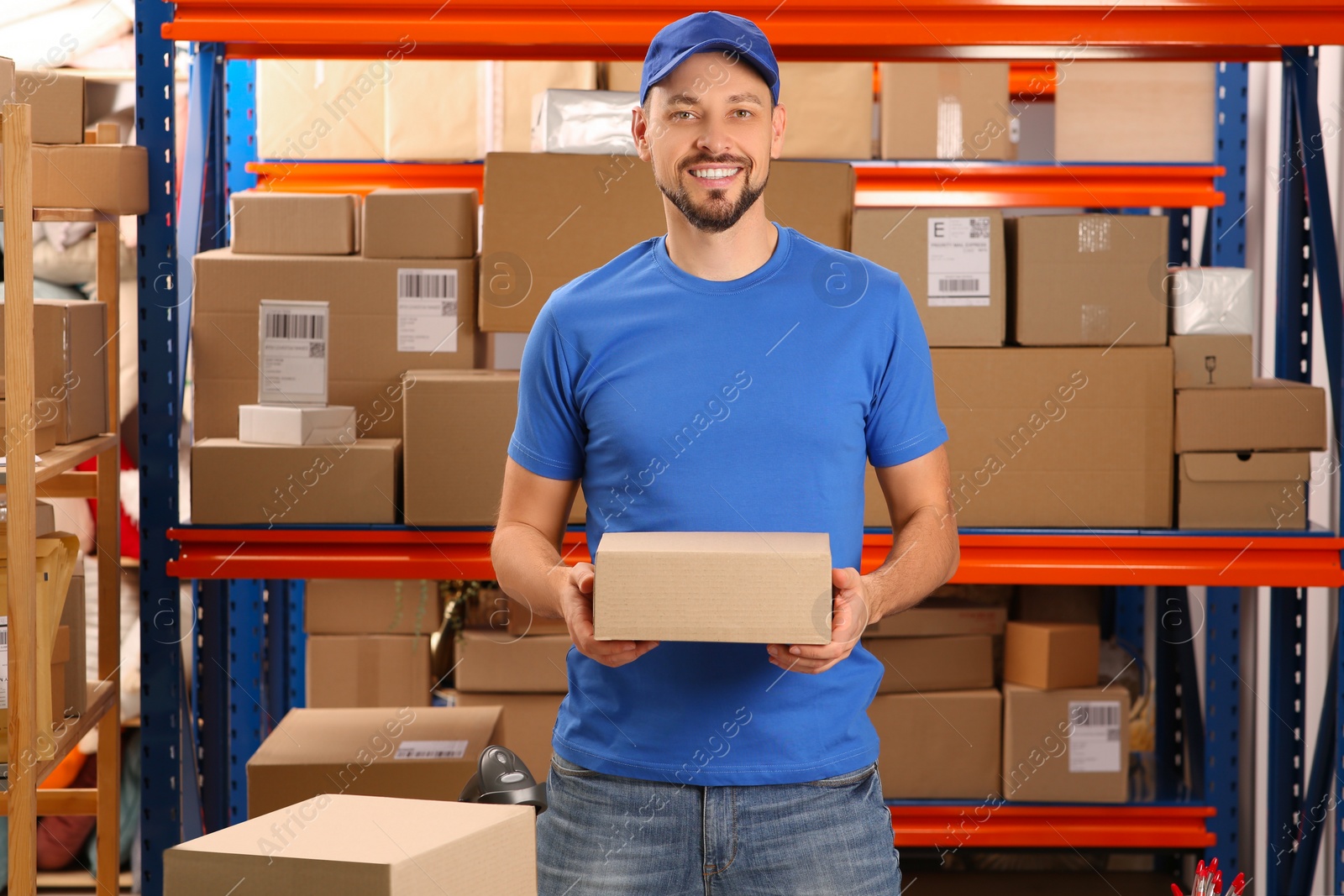 Photo of Post office worker with parcel near rack indoors