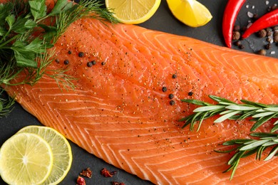 Fresh raw salmon and ingredients for marinade on black table, flat lay