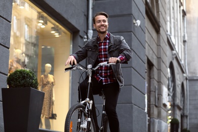 Handsome happy man riding bicycle on city street
