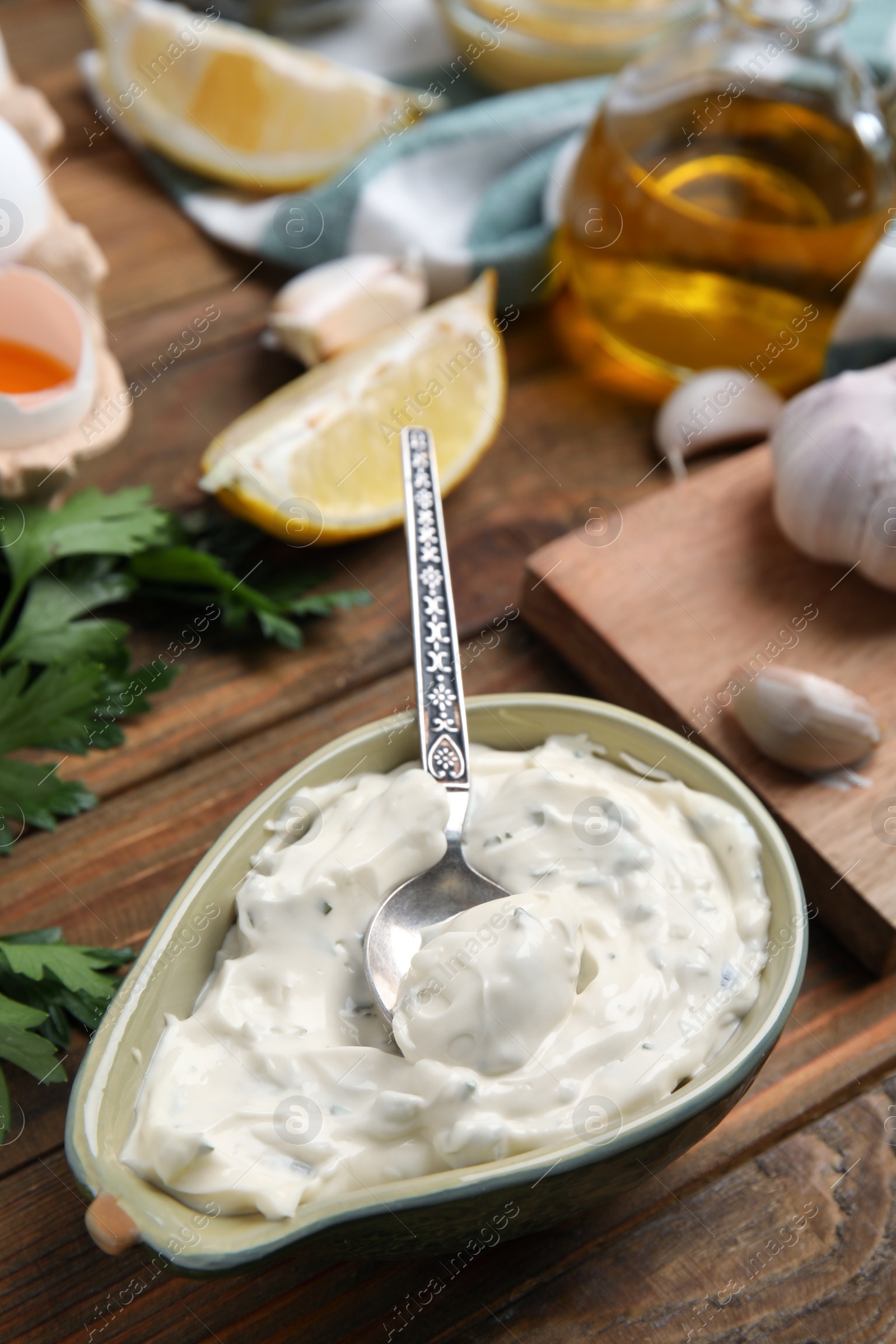 Photo of Tasty tartar sauce and ingredients on wooden table