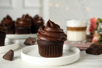 Photo of Plate with delicious chocolate cupcake on white wooden table