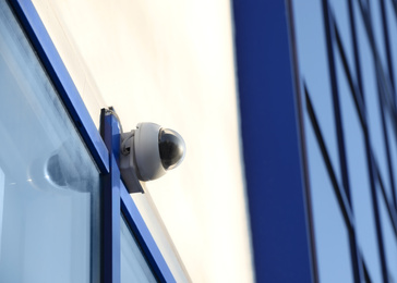 Photo of Modern CCTV camera on building wall outdoors